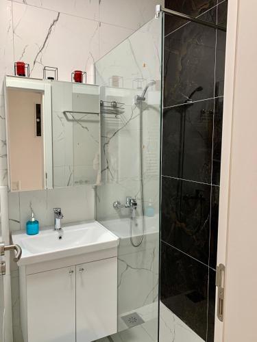 a white bathroom with a shower and a sink at Blini Studio Apartment in Pristina