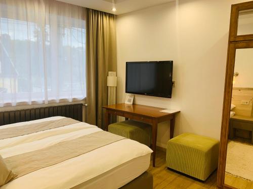 a hotel room with a bed and a flat screen tv at Egria Apartments in Eger