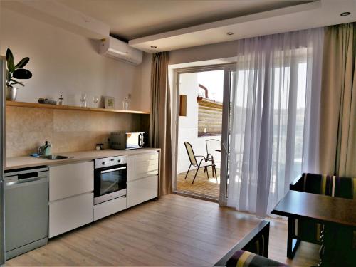 cocina con armarios blancos, mesa y comedor en Egria Apartments, en Eger