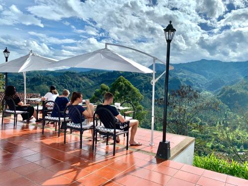 um grupo de pessoas sentadas numa mesa sob um guarda-chuva em Hotel El Mirador del Cocora em Salento