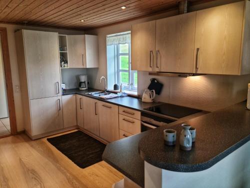 a kitchen with wooden cabinets and a black counter top at Three bedroom vacation home in Við Gjógv