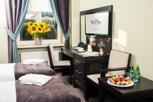 a room with two beds and a desk with a bowl of fruit at Hotel Ilan in Lublin