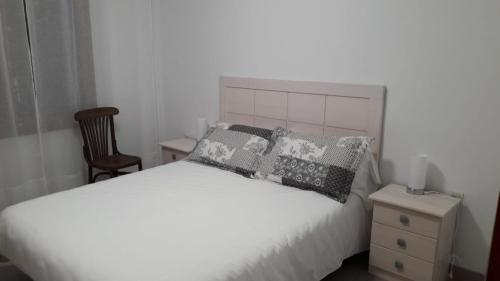 um quarto com uma cama branca com almofadas e uma cadeira em Cal Pairet 1 em Campelles