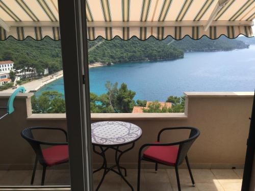 a balcony with a table and chairs and a view of a lake at Apartments Ladesta in Lastovo