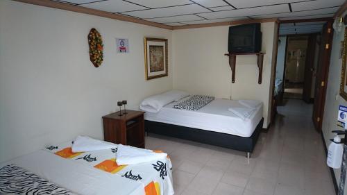 2 camas en una habitación con TV en la pared en Apartamento Rosita en Jardin