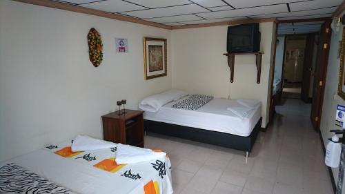 two beds in a room with a tv on the wall at Apartamento Rosita in Jardin