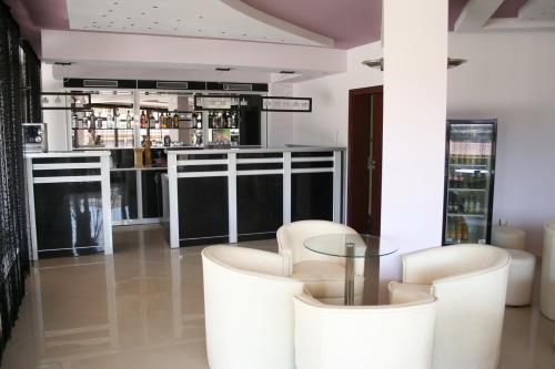 um bar com cadeiras brancas e uma mesa de vidro em Hotel Akre em Kavarna