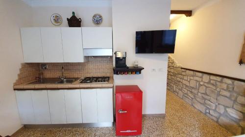 a kitchen with white cabinets and a red refrigerator at Appartamento La Cupola in Santa Maria degli Angeli