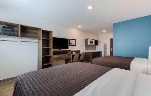 a hotel room with two beds and a flat screen tv at WoodSpring Suites Allentown in Allentown