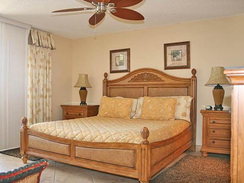 a bedroom with a wooden bed with two dressers and a fan at Mainsail II in Destin