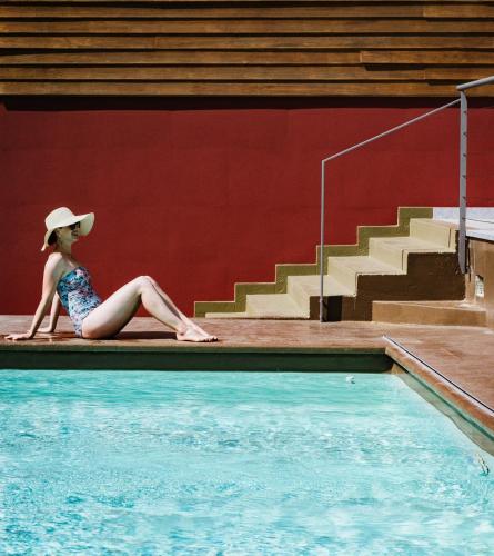 a woman in a hat sitting next to a swimming pool at Lake Hotel La Pieve in Pisogne
