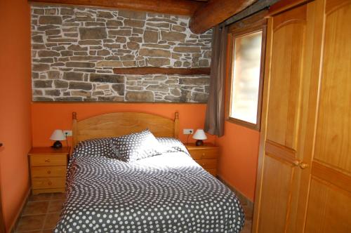 a bedroom with a bed and a stone wall at Apartamentos Borda Falceto in Coscojuela de Sobrarbe