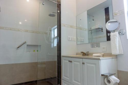 uma casa de banho com um chuveiro, um lavatório e um espelho. em Frederick's Lodge em Kumasi