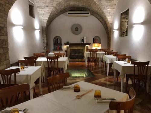 a restaurant with white tables and chairs and a fireplace at Hotel La Fortezza in Assisi