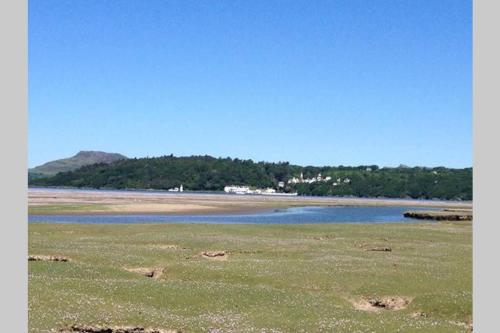 a beach with a body of water and a mountain at The Little Boat House in Talsarnau