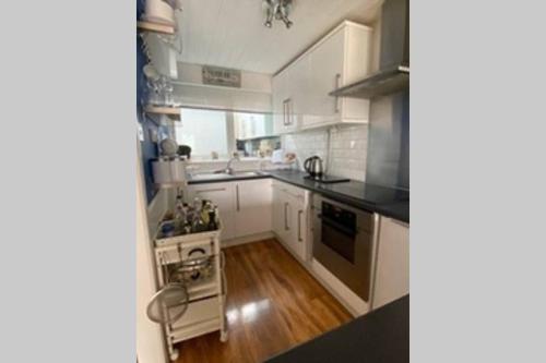 a kitchen with white cabinets and a stove top oven at The Little Boat House in Talsarnau