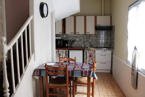 une cuisine avec une table, des chaises et une horloge dans l'établissement maisonnette, 5003, à Rochefort