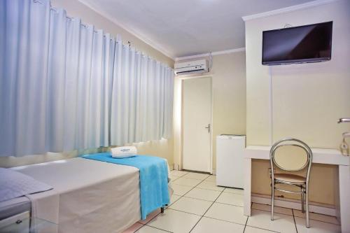 a bedroom with a bed and a chair and a television at Exclusive Hotel in Petrolina