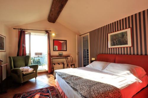 a bedroom with a bed and a chair and a window at Felicin - Villa Stella in Monforte dʼAlba