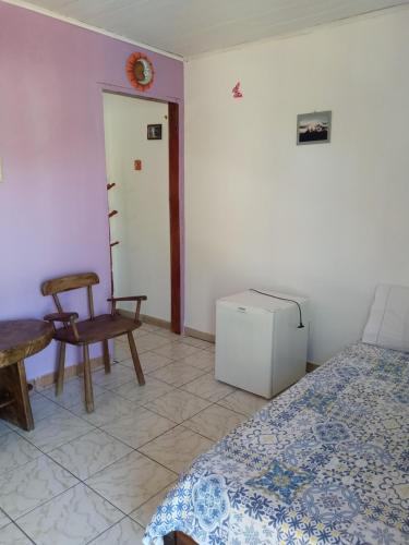 a bedroom with a bed and a chair and a table at Suítes Novo Amanhecer in Sao Jorge