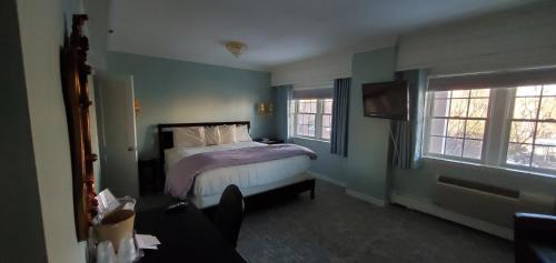 a bedroom with a bed and two windows at Lowell Inn in Stillwater
