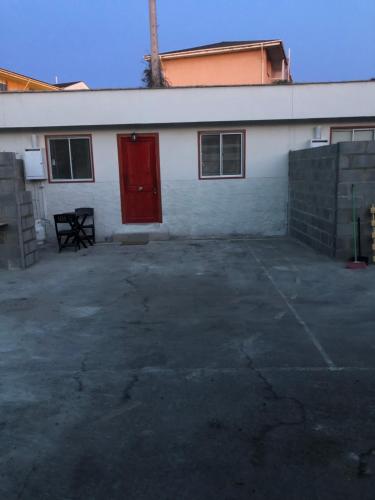 a white building with a red door in a parking lot at Cabañas Costatour Quintero in Quintero