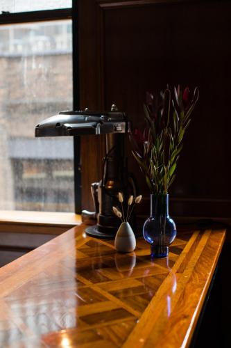 a wooden table with a vase of flowers on it at The Old Clare by Ode Hotels in Sydney
