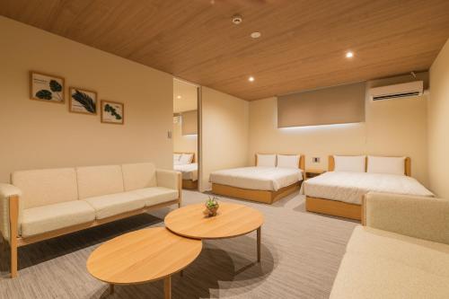 Habitación con 2 camas, sofá y mesa. en HOTEL All Stay Hakata Kukodori, en Fukuoka