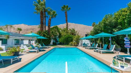 a pool with chairs and umbrellas at a resort at BelleVue Oasis - Adults Only in Palm Springs