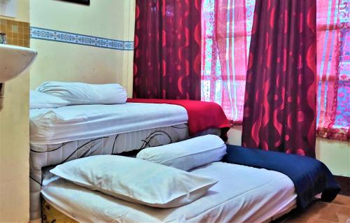 two beds in a room with red curtains at Katawa Guest House Syariah in Sukarami