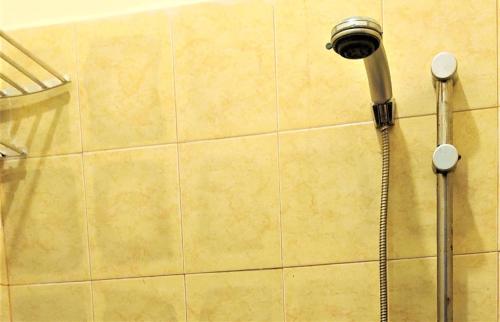 una ducha con cabezal de ducha en una pared de azulejos en Katawa Guest House Syariah, en Sukarami