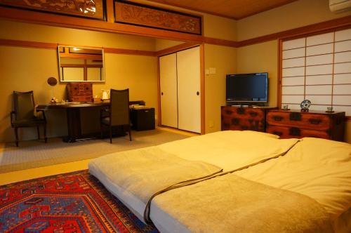 a bedroom with a bed and a table and a television at Atelier Bee's Knees Bed & Breakfast in Ikuma