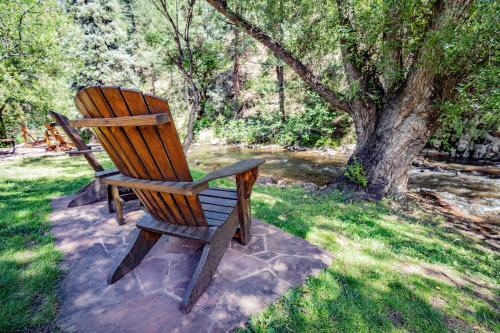 a wooden chair sitting in the grass next to a tree at Colorado Bear Creek Cabins in Evergreen
