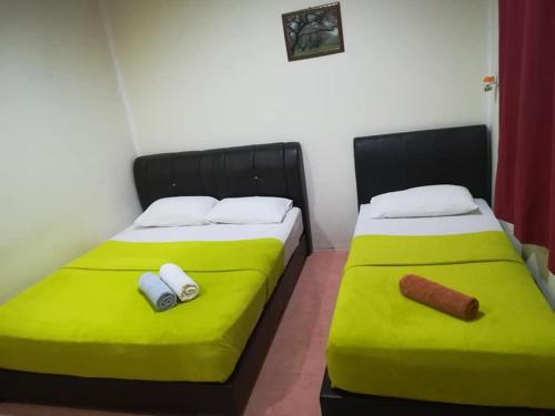 dwa łóżka z zieloną pościelą w pokoju w obiekcie Tokman Inn w mieście Pantai Cenang