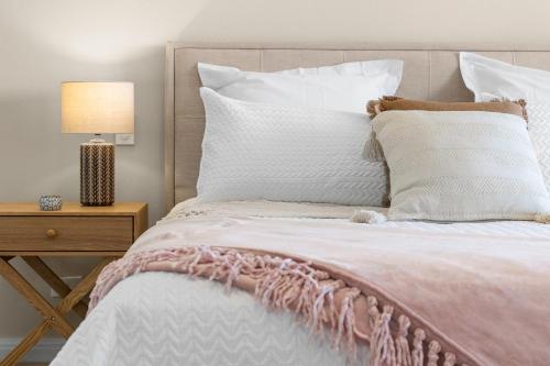 a bed with white pillows and a pink blanket at Shawhaven in East Ballina
