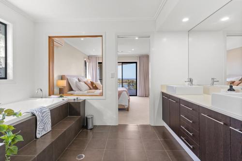 a bathroom with a large tub and a large mirror at Shawhaven in East Ballina