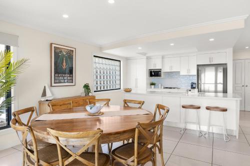 a kitchen and dining room with a wooden table and chairs at Shawhaven in East Ballina