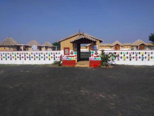 a small house with a white wall and a yard at Banni Village Resort - Rann Of Kutch in Bherandiāla