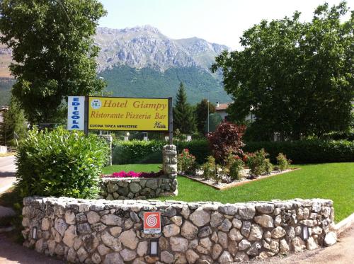 um sinal para um resort com uma parede de pedra em Hotel Giampy em Assergi