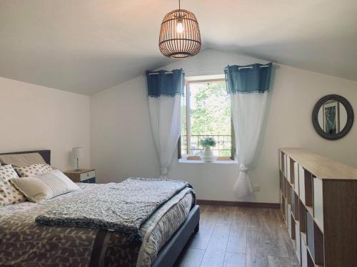 - une chambre avec un lit doté de rideaux bleus et d'une fenêtre dans l'établissement L'étape du moulin, à Barbaste