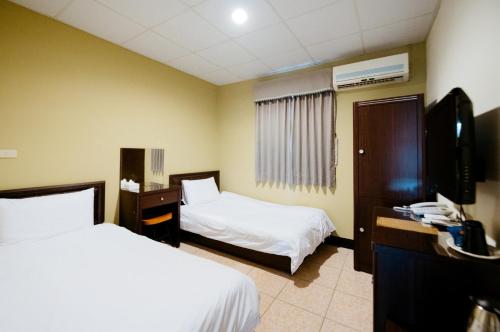 a hotel room with two beds and a television at 金鷺民宿 in Jincheng