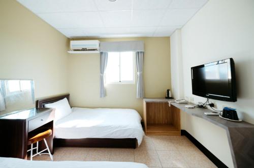 a hotel room with two beds and a flat screen tv at 金鷺民宿 in Jincheng