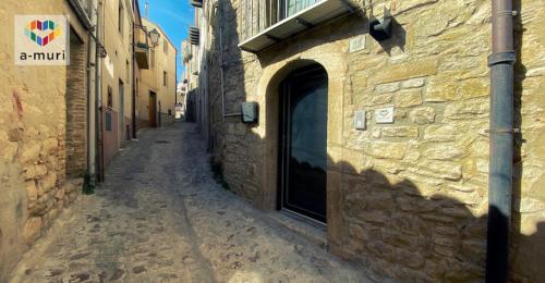 un callejón con un edificio de piedra y una puerta en A-MURI, en Gangi