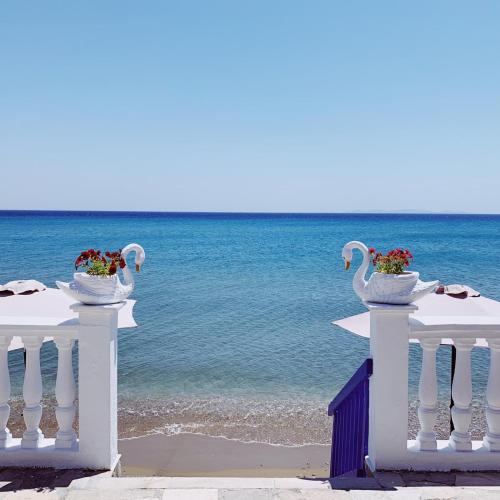 two white tables with vases on the beach at Potokaki Beachfront Hotel in Pythagoreio