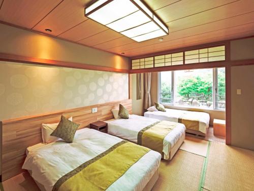 a hotel room with two beds and a window at SPA HOTEL YUTTARIKAN in Satsumasendai
