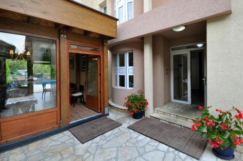 a house with glass doors and flowers on a patio at Sunny Hill Apartments & Aqua Park in Vrnjačka Banja