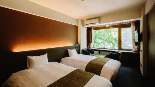 a hotel room with two beds and a window at Kyu-Karuizawa Hotel Shinonome in Karuizawa