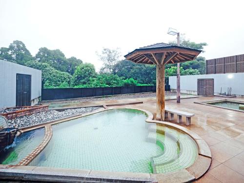 a large swimming pool with an umbrella on a patio at SPA HOTEL YUTTARIKAN in Satsumasendai