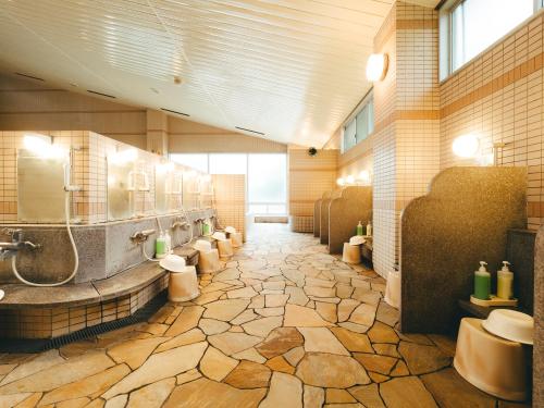 un baño grande con suelo de piedra, lavabos y aseos en SPA HOTEL YUTTARIKAN en Satsumasendai