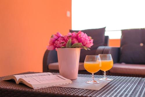 a table with a vase of flowers and two glasses of orange juice at Apartments Orange Medulin in Medulin